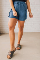 BLONDE WOMAN WEARING SCUBA THIGH POCKET SHORTS WITH ELASTIC WAIST & DRAWSTRING. 