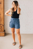 BLONDE WOMAN WEARING SCUBA THIGH POCKET SHORTS WITH ELASTIC WAIST & DRAWSTRING. 