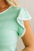 Mint green top with white trim on a neutral background