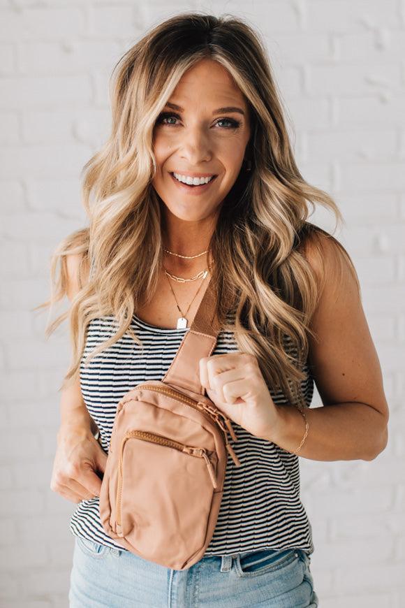 Woman wearing a camel colored nylon monochromatic crossbody bag.