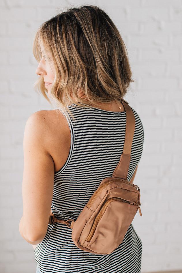 Woman wearing a camel colored nylon monochromatic crossbody bag.