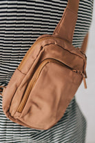 Woman wearing a camel colored nylon monochromatic crossbody bag.