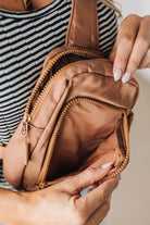 Woman wearing a camel colored nylon monochromatic crossbody bag.