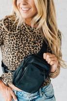 Blonde woman in a leopard tee shirt wearing a black Essential Nylon Crossbody bag.