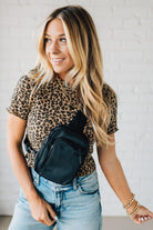 Blonde woman in a leopard tee shirt wearing a black Essential Nylon Crossbody bag.
