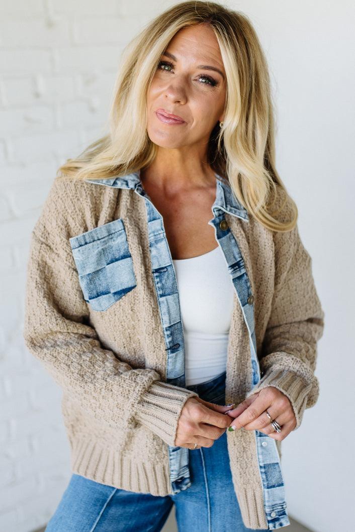 Woman wearing a beige cardigan with denim accents against a white background