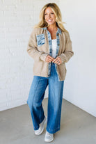 Woman wearing a beige cardigan with a denim trim with a white background