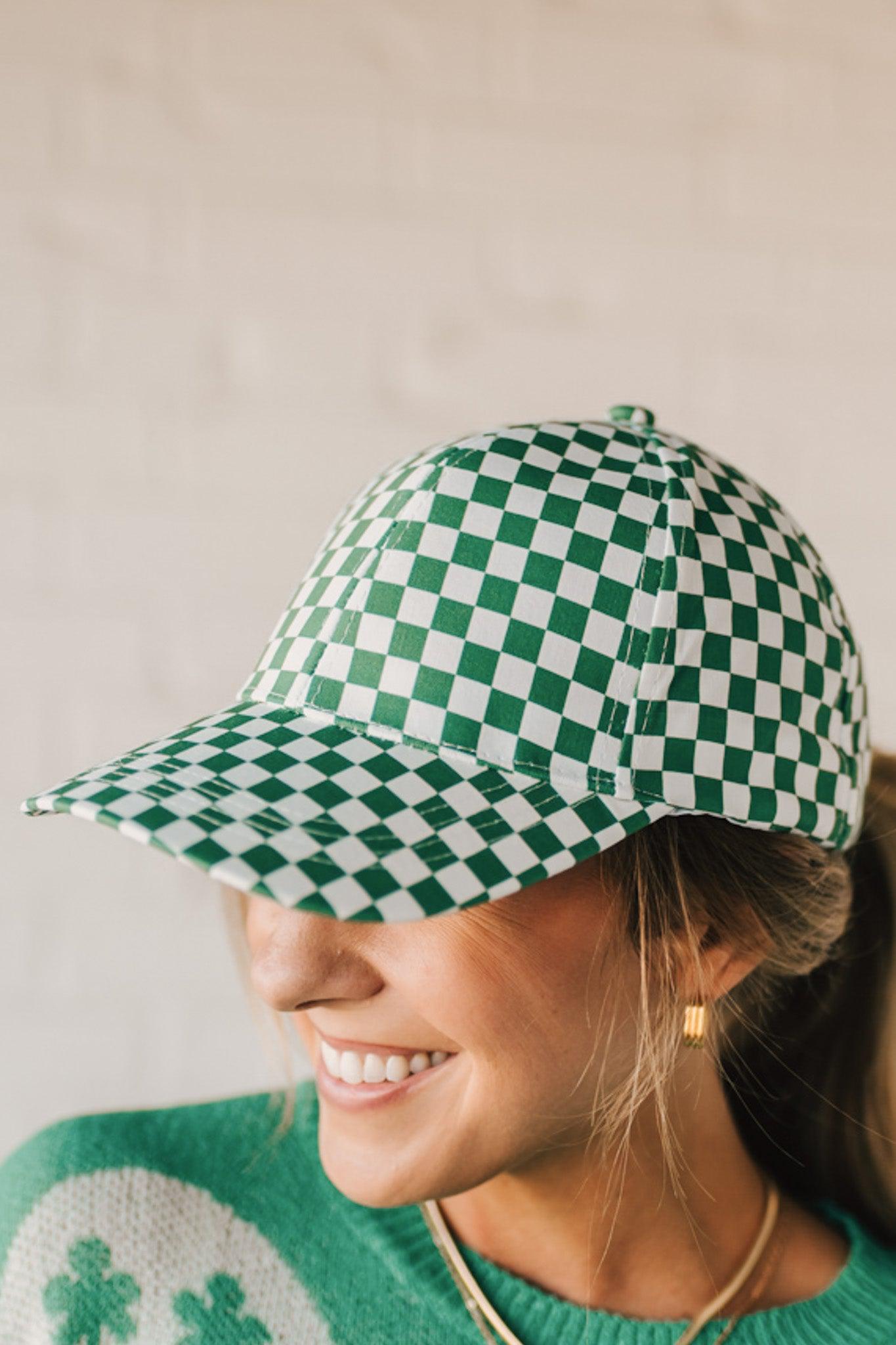 Blonde woman wearing a green and white checkered ball cap. 