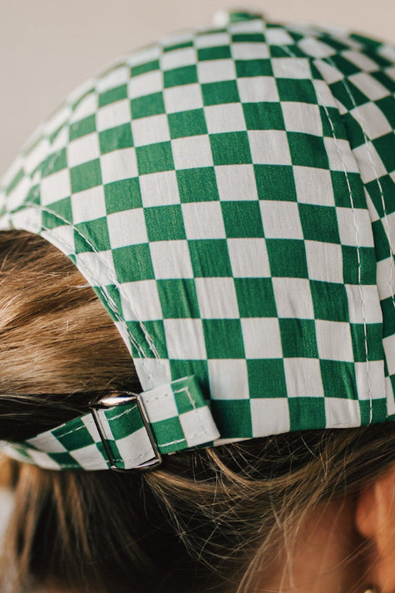 Blonde woman wearing a green and white checkered ball cap. 