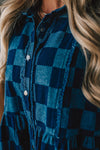 Blonde woman wearing a hat and boots with checkered denim knee length dress.