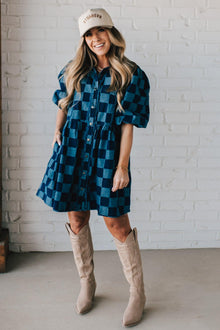  Blonde woman wearing a hat and boots with checkered denim knee length dress.