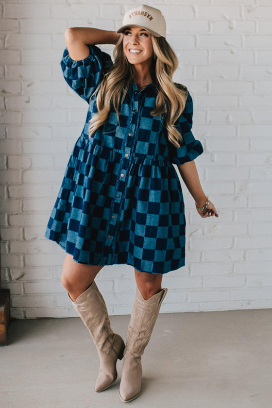 Blonde woman wearing a hat and boots with checkered denim knee length dress.