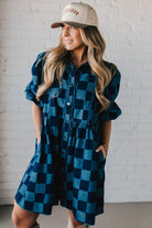 Blonde woman wearing a hat and boots with checkered denim knee length dress.