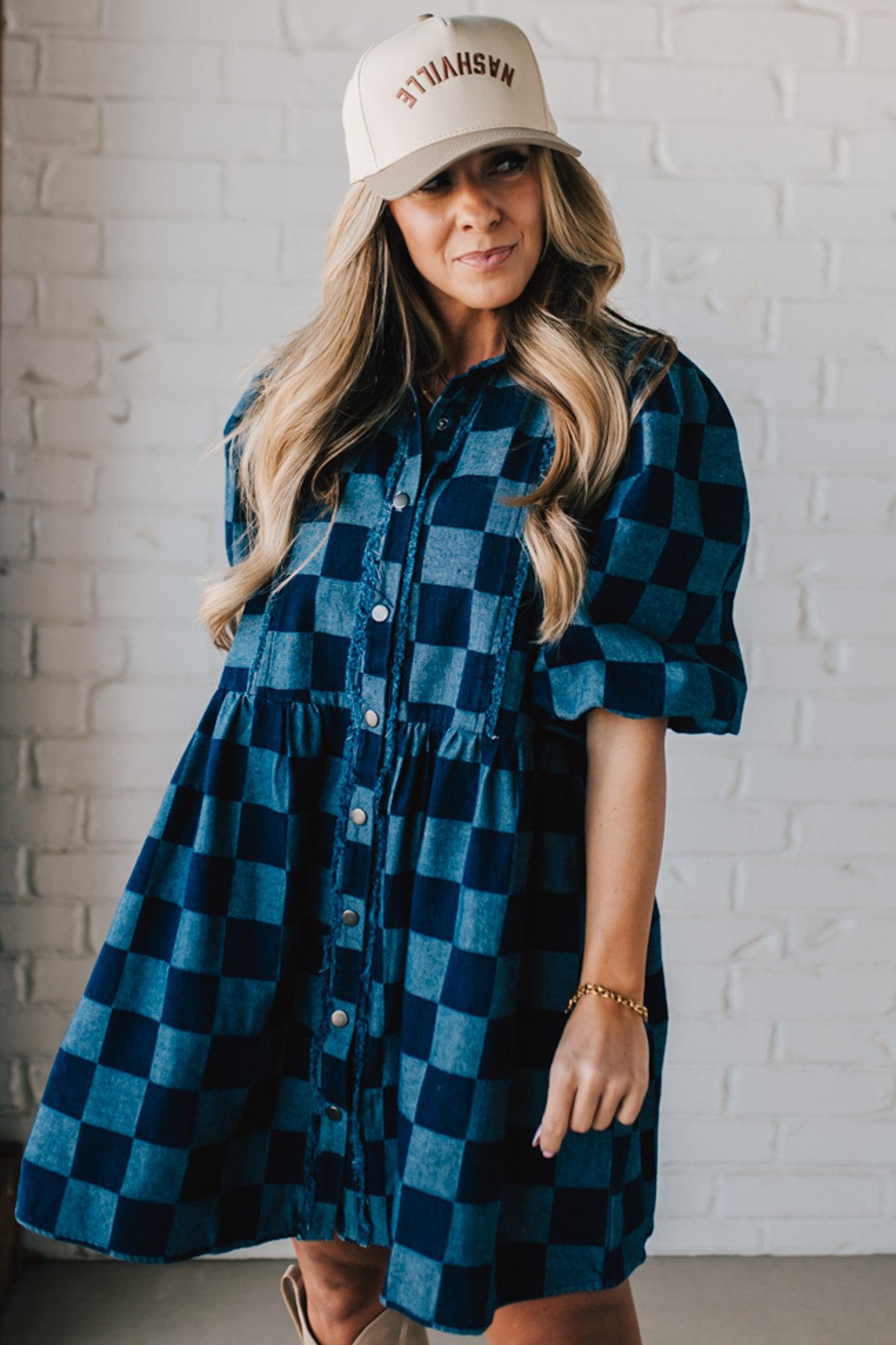 Blonde woman wearing a hat and boots with checkered denim knee length dress.