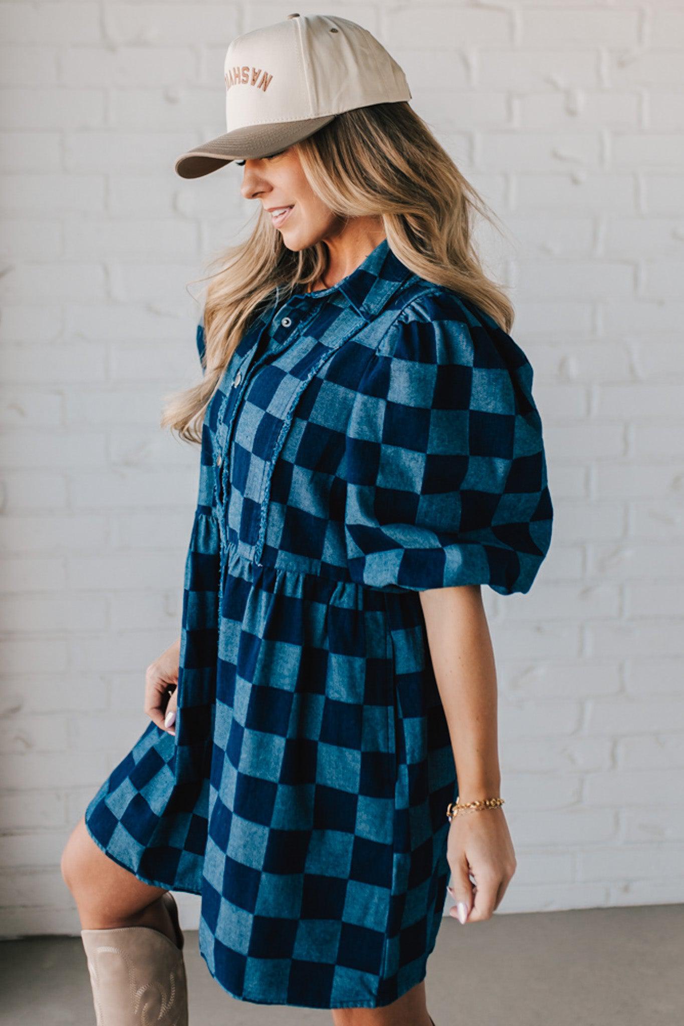 Blonde woman wearing a hat and boots with checkered denim knee length dress.