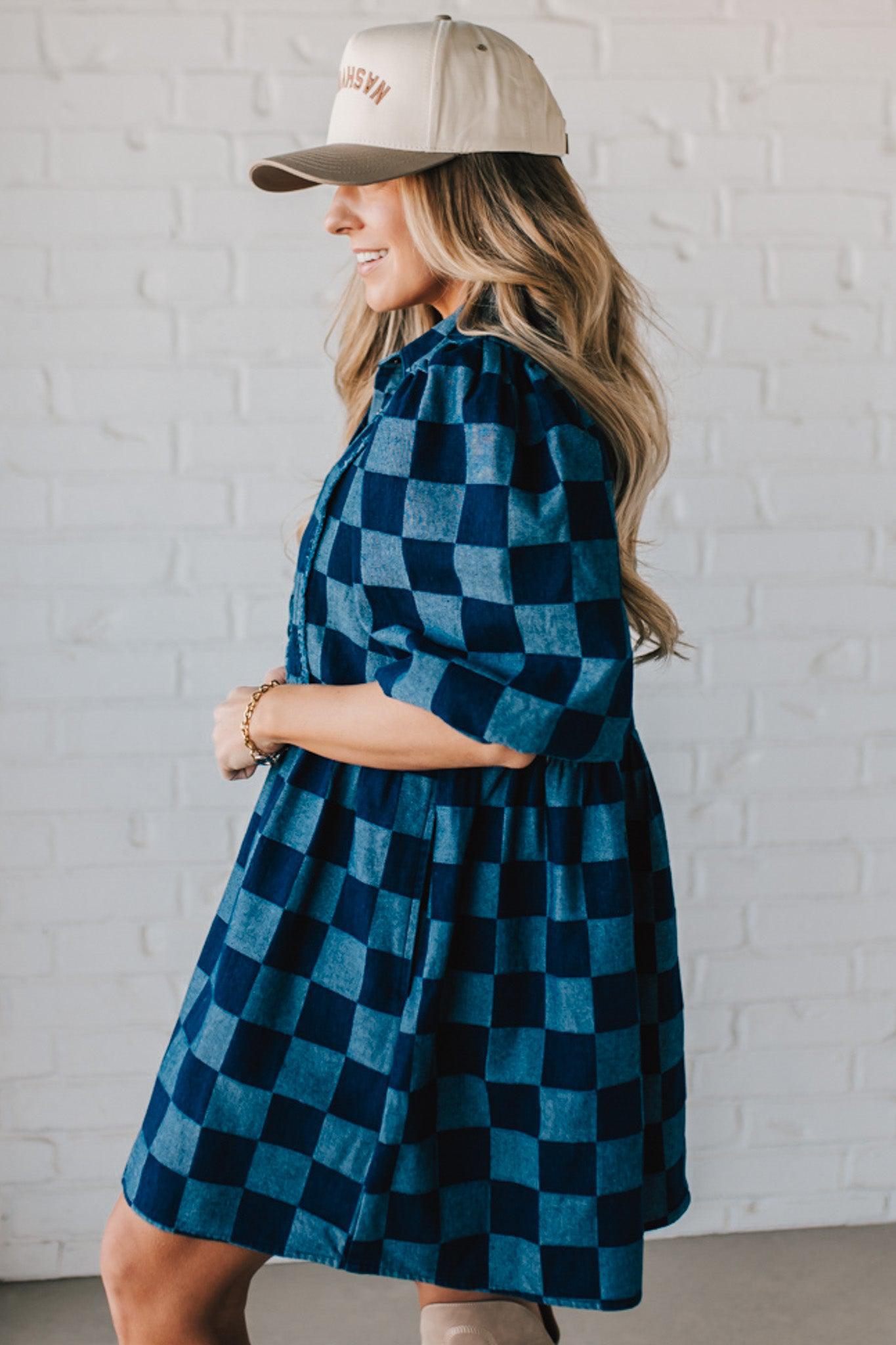 Blonde woman wearing a hat and boots with checkered denim knee length dress.