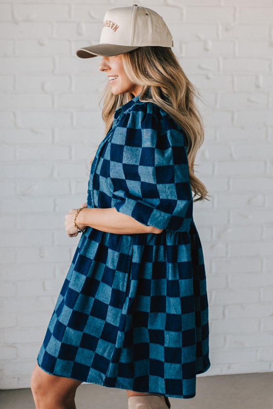 Blonde woman wearing a hat and boots with checkered denim knee length dress.