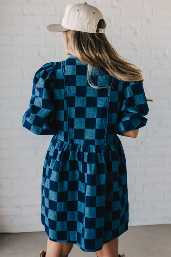 Blonde woman wearing a hat and boots with checkered denim knee length dress.