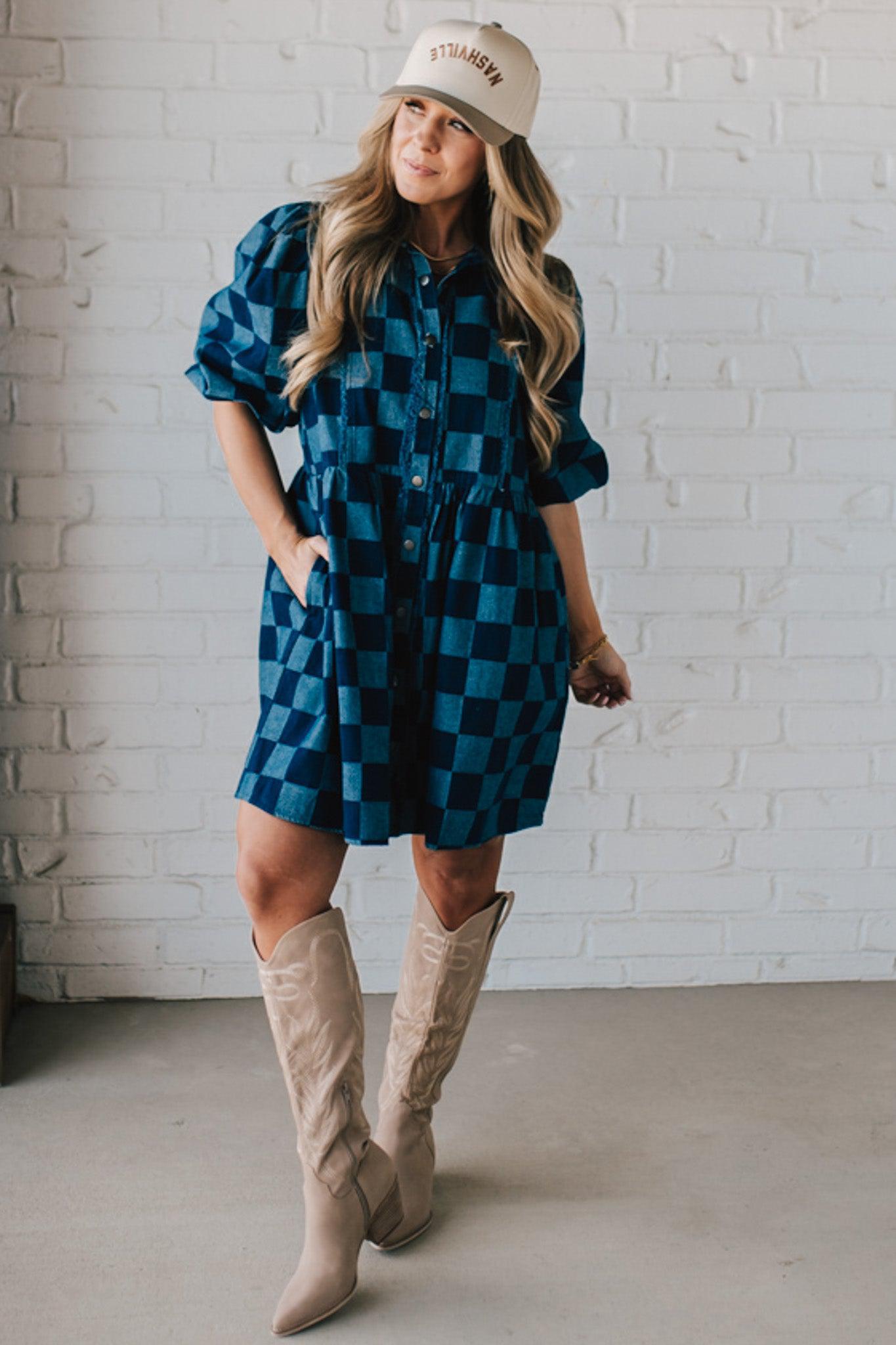 Blonde woman wearing a hat and boots with checkered denim knee length dress.