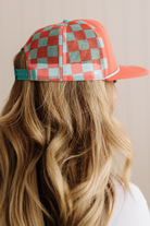 Person wearing a checkered cap with a red and green pattern on a neutral background