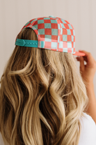 Person wearing a checkered cap with wavy hair against a neutral background