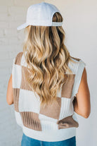 Person wearing a checkered vest and white cap with a neutral background