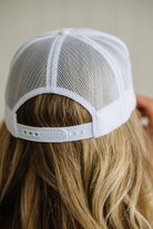 White mesh cap worn by a person with blonde hair against a neutral background