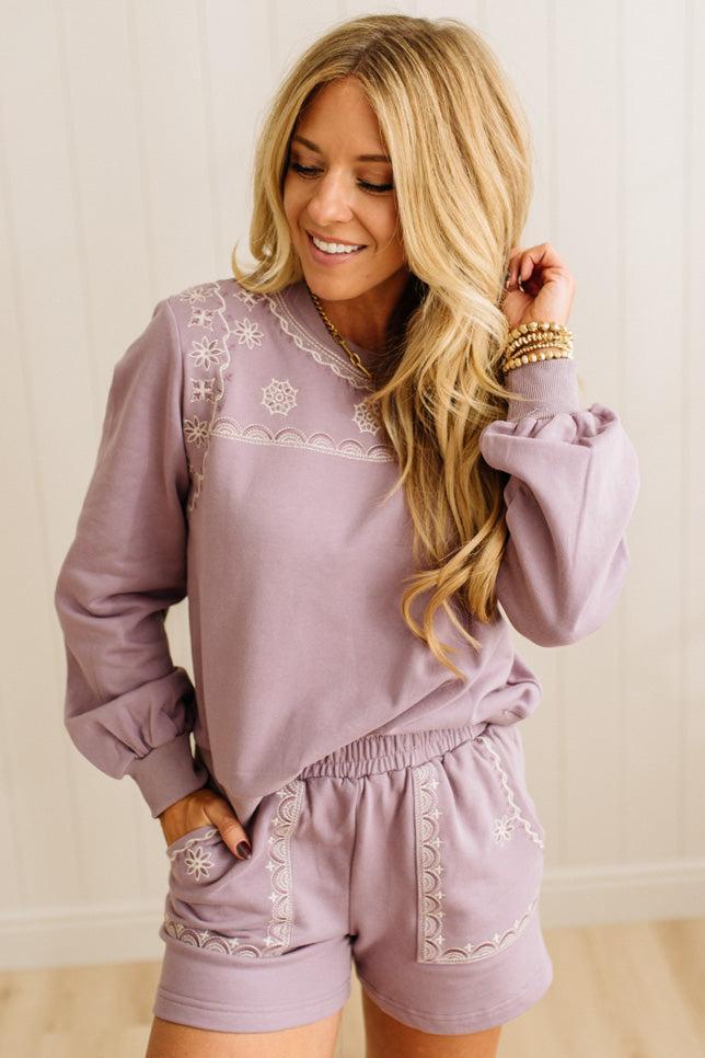 Woman wearing a lavender loungewear set with embroidery details.