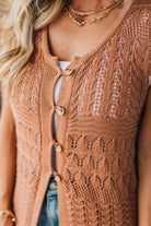 Brown knitted cardigan worn by a person with gold jewelry.