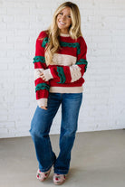 BLONDE WOMAN WEARING A CHRISTMAS THEME RUFFLED DETAILS SWEATER TOP IN RED, CREAM, AND HUNTER GREEN.