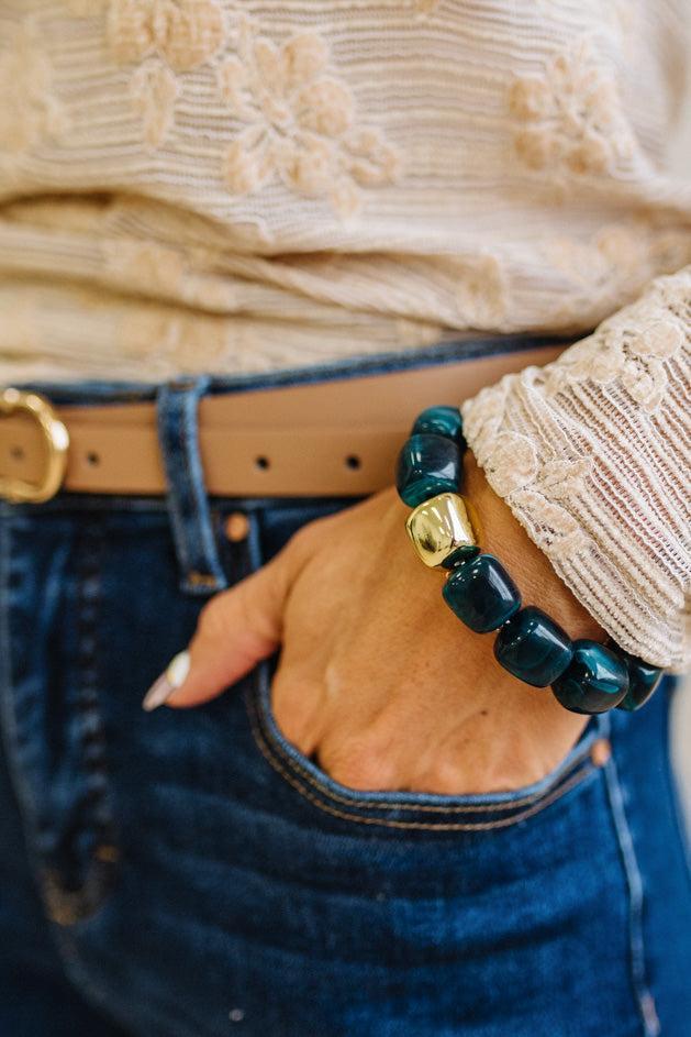 Dark Cyan bead bracelet with a gold accent bead shown on a woman's wrist in her pocket.
