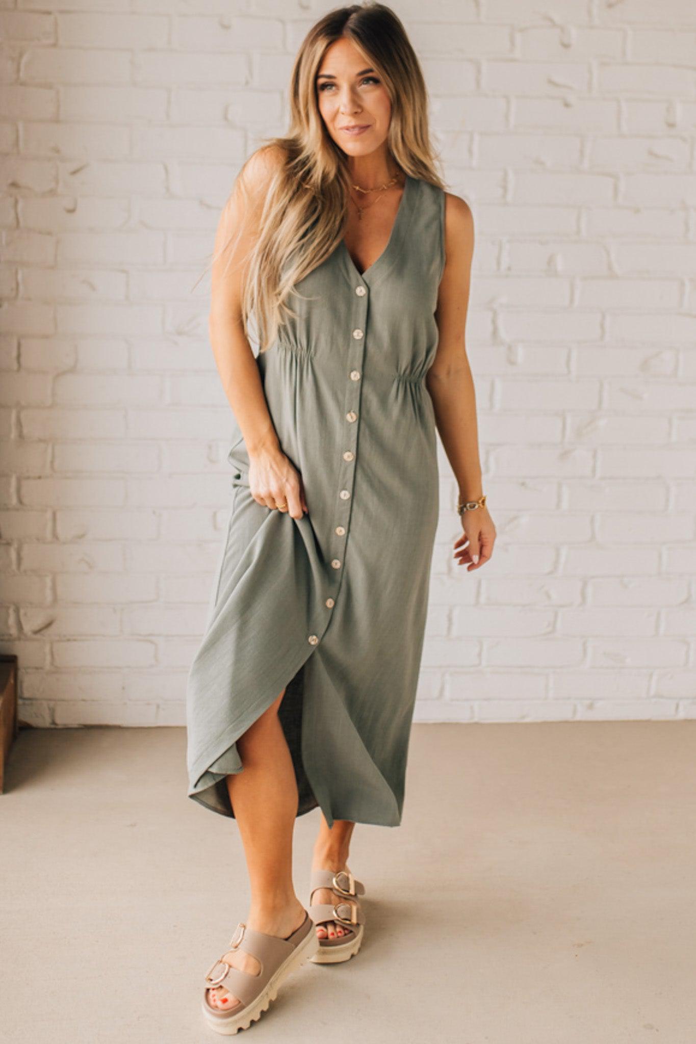 BLONDE WOMAN WEARING A LIGHT OLIVE LINEN BLEND V NECK BUTTON DOWN SLEEVELESS DRESS.