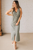 BLONDE WOMAN WEARING A LIGHT OLIVE LINEN BLEND V NECK BUTTON DOWN SLEEVELESS DRESS.