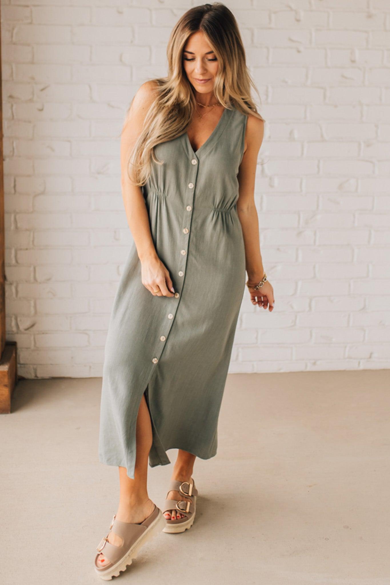 BLONDE WOMAN WEARING A LIGHT OLIVE LINEN BLEND V NECK BUTTON DOWN SLEEVELESS DRESS.