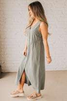 BLONDE WOMAN WEARING A LIGHT OLIVE LINEN BLEND V NECK BUTTON DOWN SLEEVELESS DRESS.