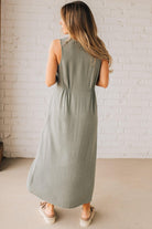 BLONDE WOMAN WEARING A LIGHT OLIVE LINEN BLEND V NECK BUTTON DOWN SLEEVELESS DRESS.