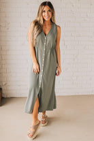 BLONDE WOMAN WEARING A LIGHT OLIVE LINEN BLEND V NECK BUTTON DOWN SLEEVELESS DRESS.