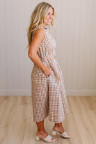 Woman wearing a checkered dress standing against a plain wall.