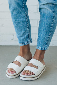  woman wearing white double strap slides with an tone on tone embroidered detail