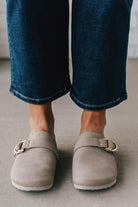 girl modeling a warm grey colored suede clog with a gold buckle