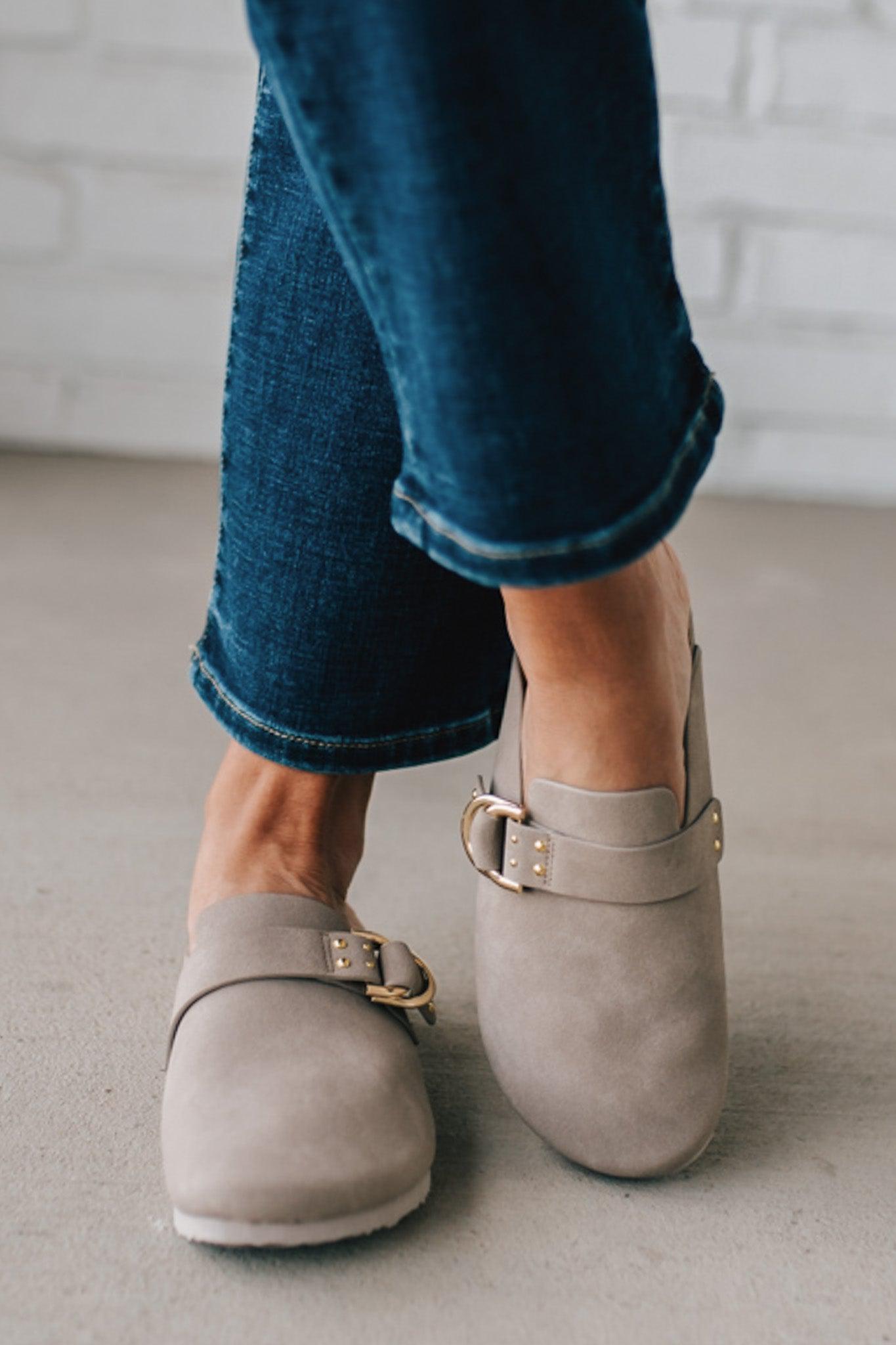 girl modeling a warm grey colored suede clog with a gold buckle