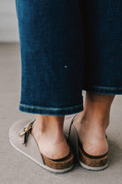 girl modeling a warm grey colored suede clog with a gold buckle