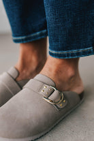 girl modeling a warm grey colored suede clog with a gold buckle