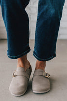 girl modeling a warm grey colored suede clog with a gold buckle