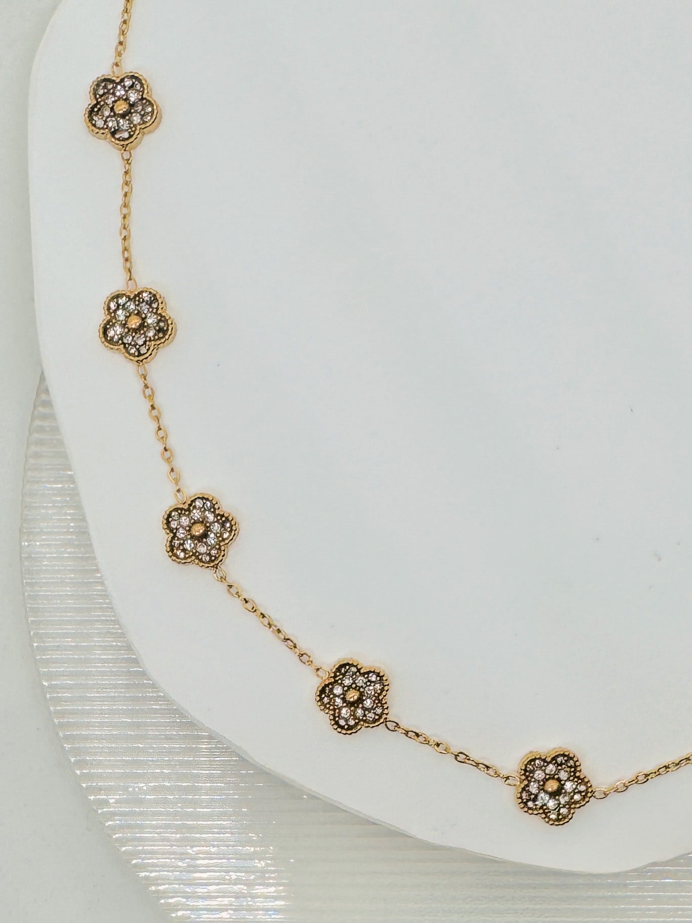 Gold bracelet with floral designs on a white plate