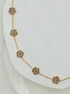 Gold bracelet with floral designs on a white plate