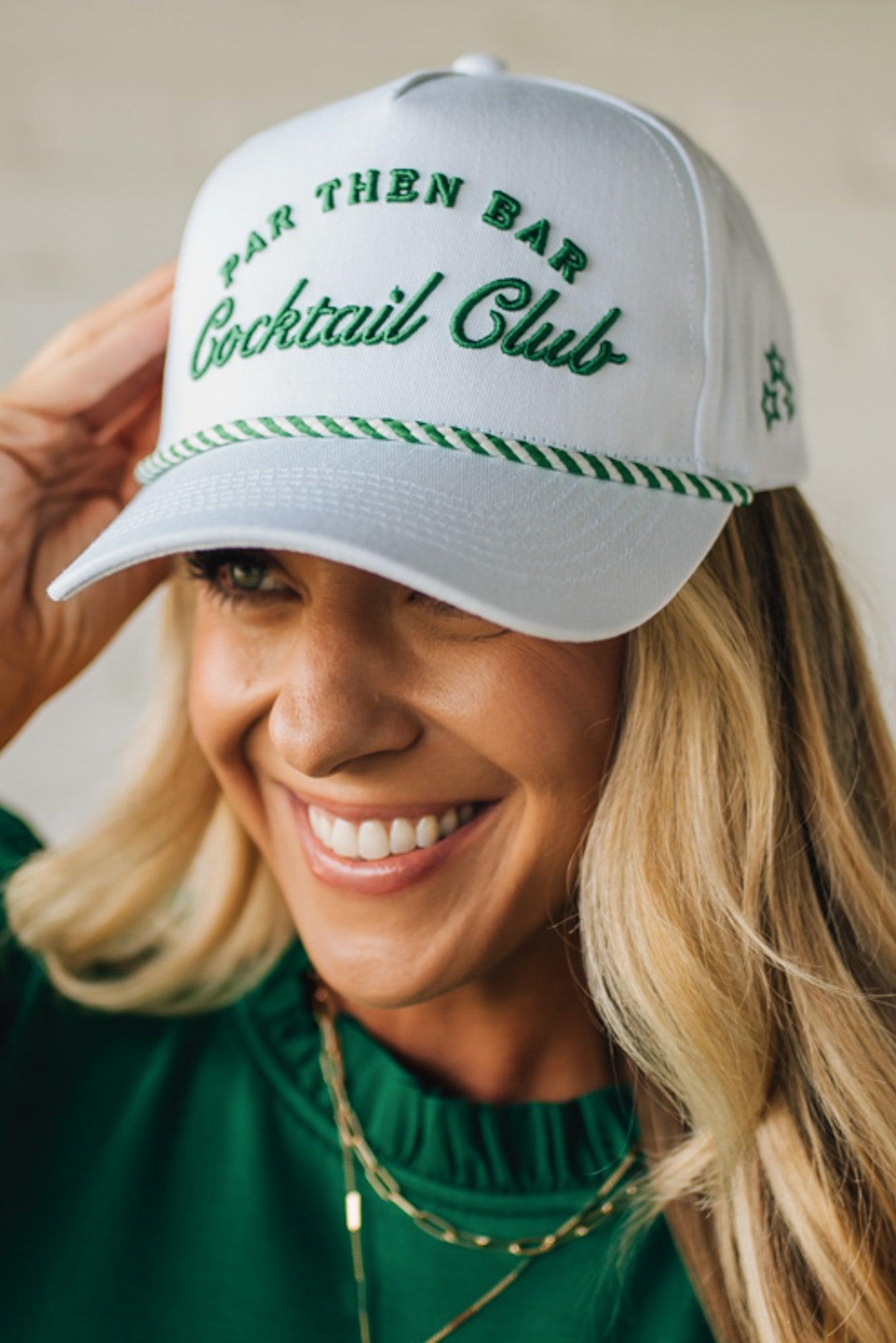 Blonde woman wearing a white hat with green embroidery and twist rope across the brim, front panel says "Par then Bar Cocktail Club"