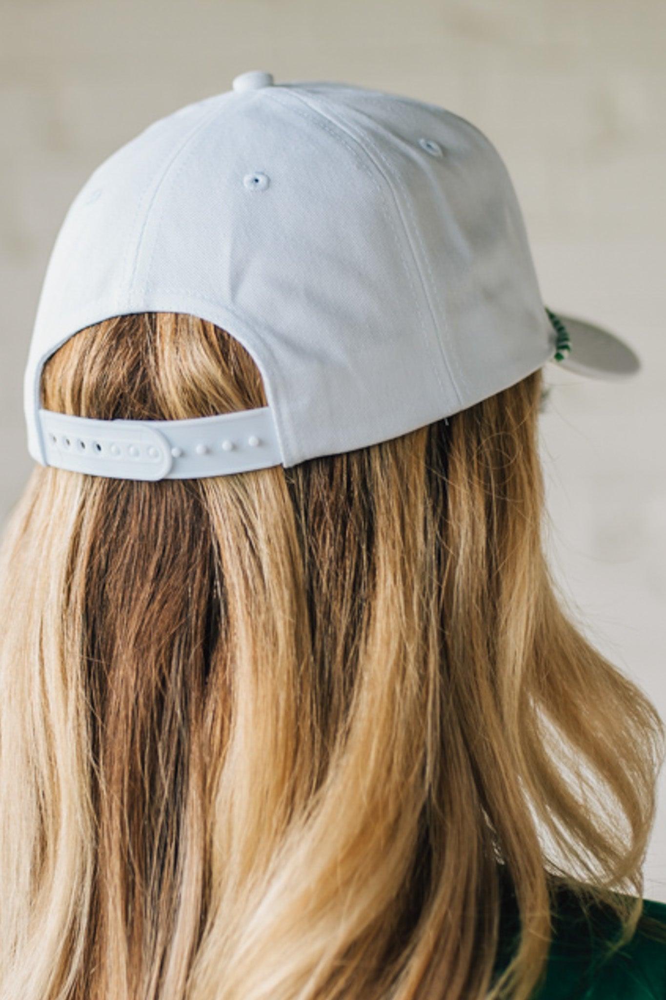 Blonde woman wearing a white hat with green embroidery and twist rope across the brim, front panel says "Par then Bar Cocktail Club"