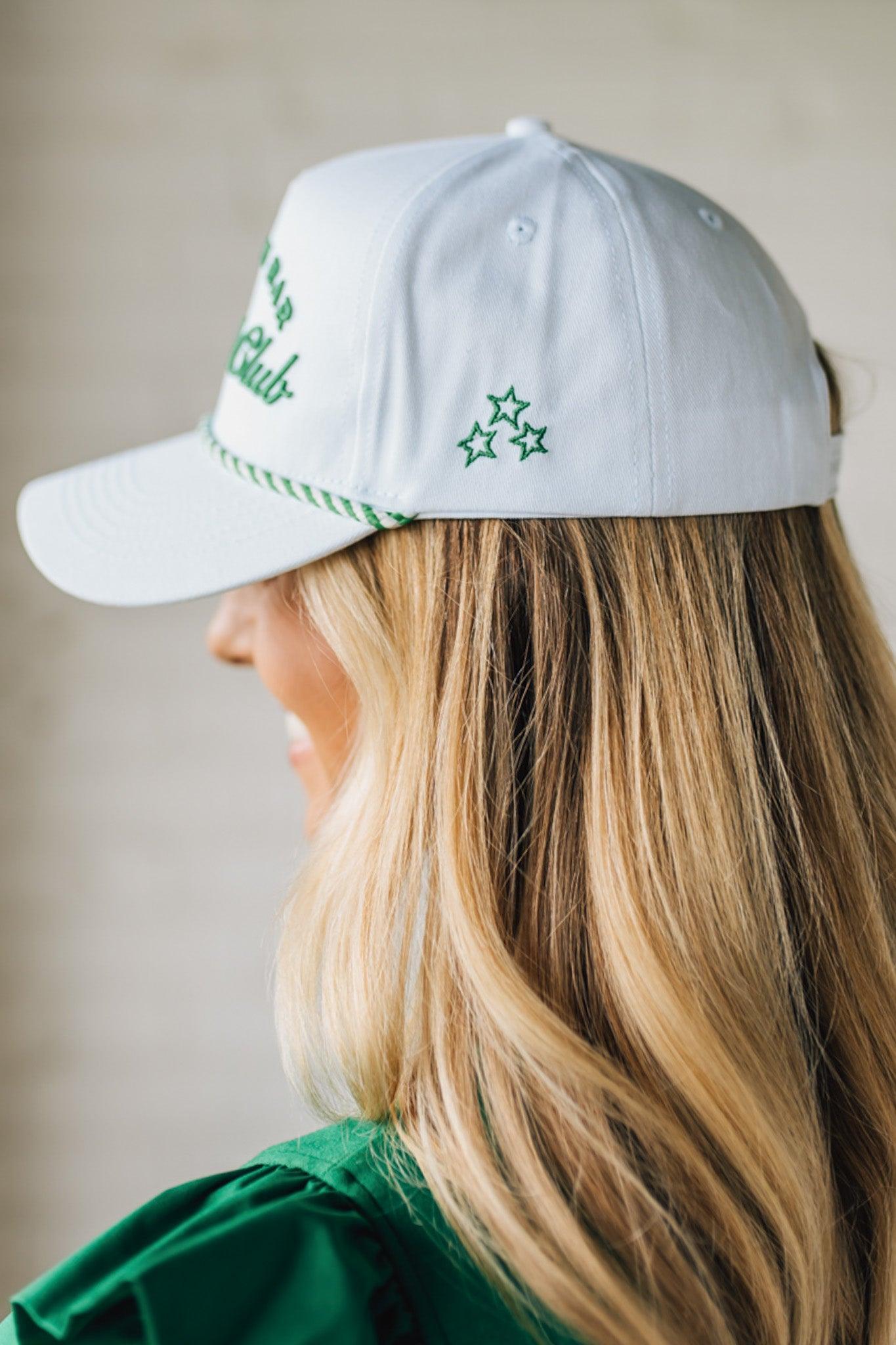Blonde woman wearing a white hat with green embroidery and twist rope across the brim, front panel says "Par then Bar Cocktail Club"