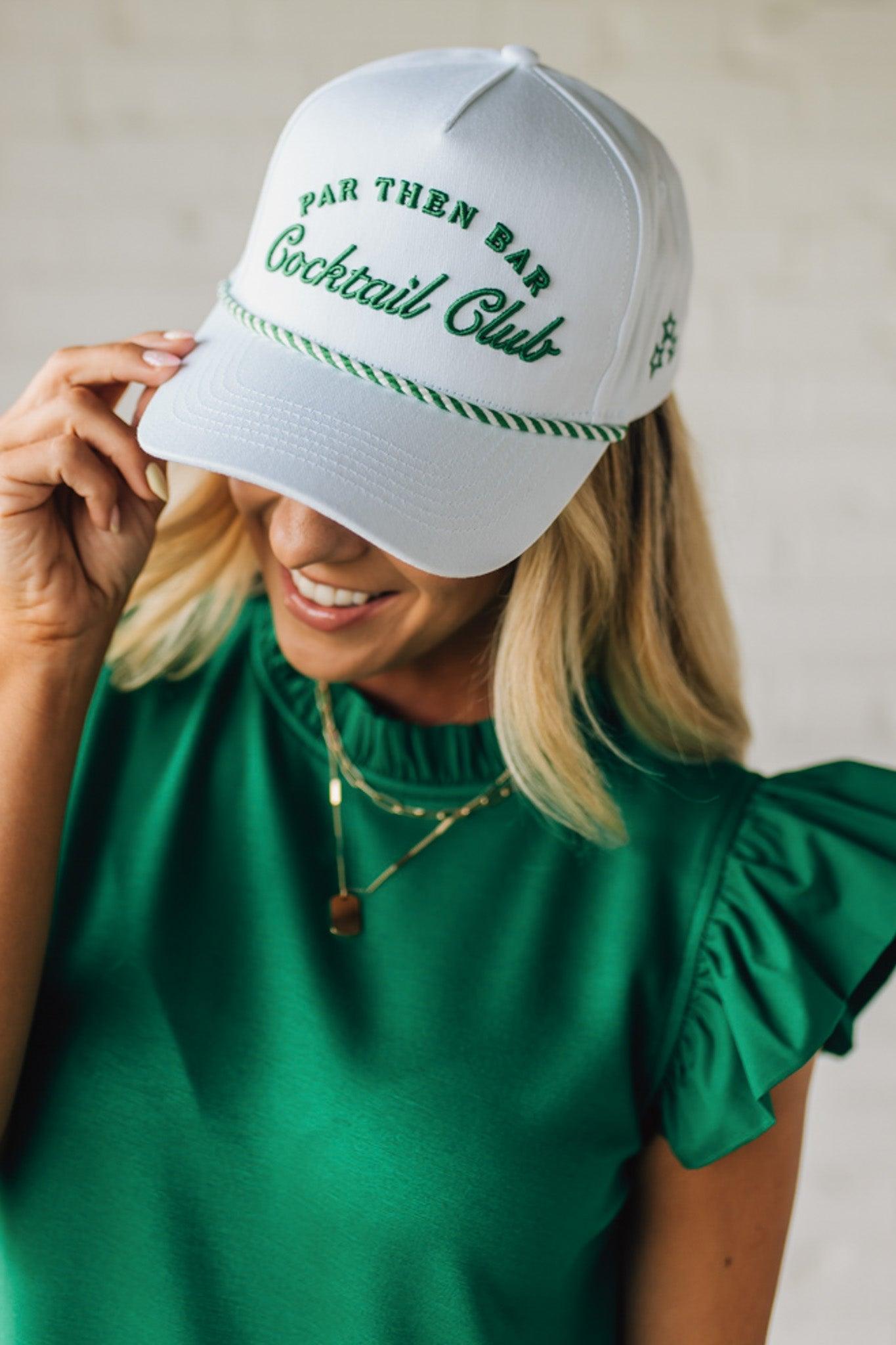 Blonde woman wearing a white hat with green embroidery and twist rope across the brim, front panel says "Par then Bar Cocktail Club"